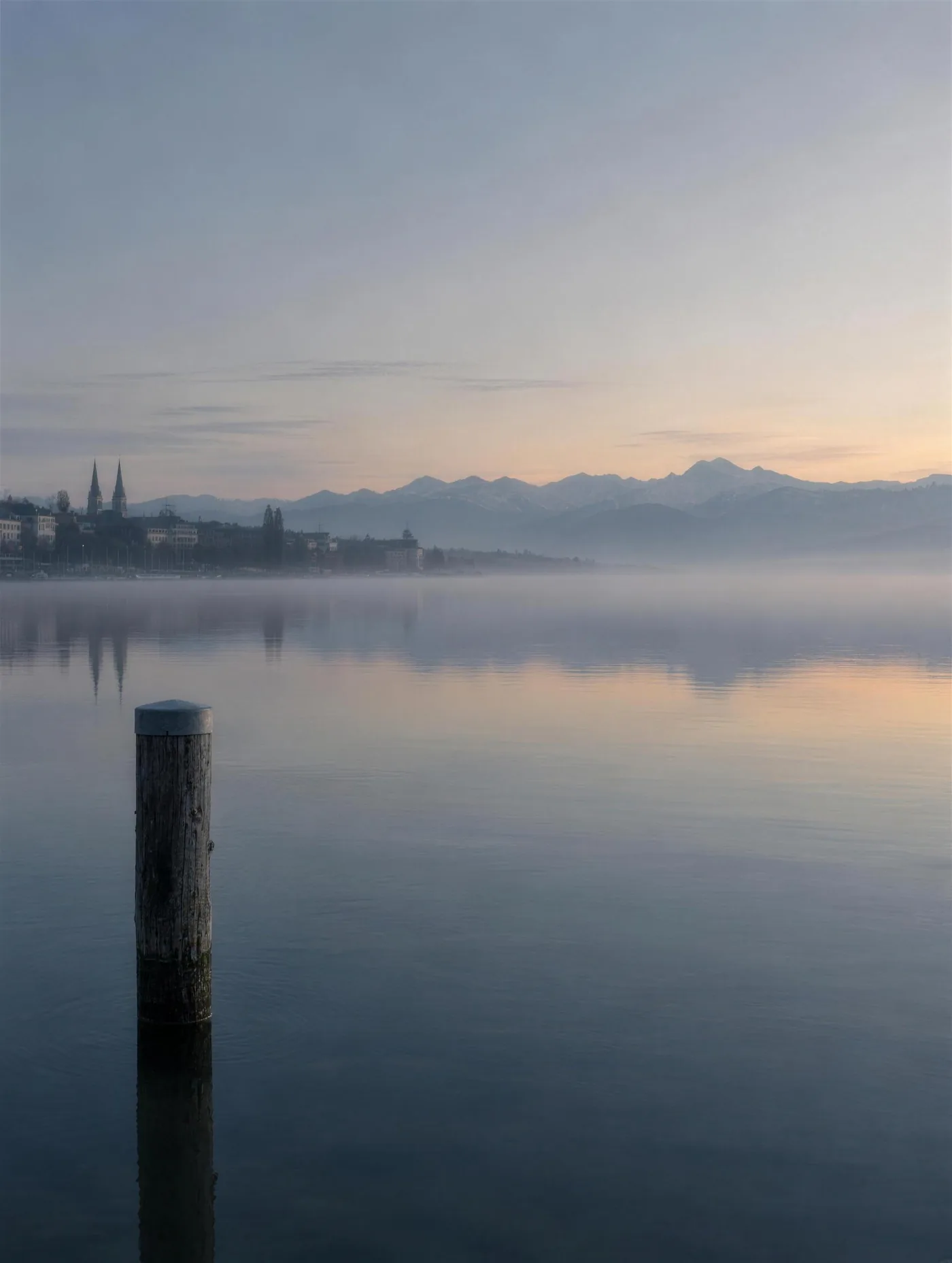 Der Zürichsee im Morgennebel mit den Alpen am Horizont